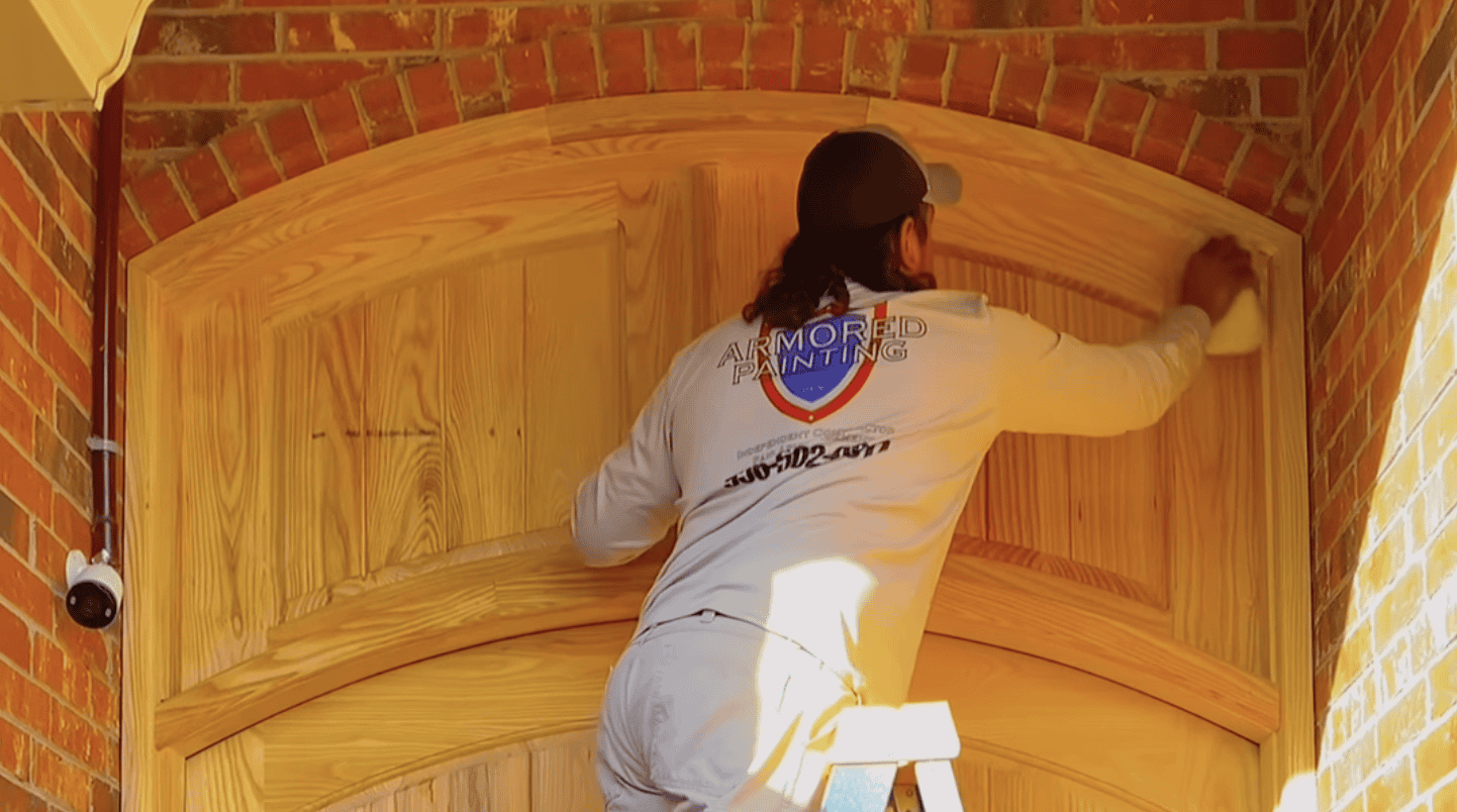 Armored Painting craftsman refinishing an arched wood front door