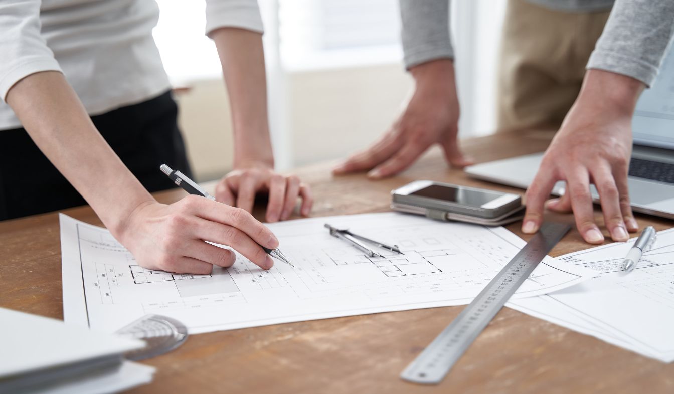 Designers and homeowners reviewing kitchen remodel plans around a table