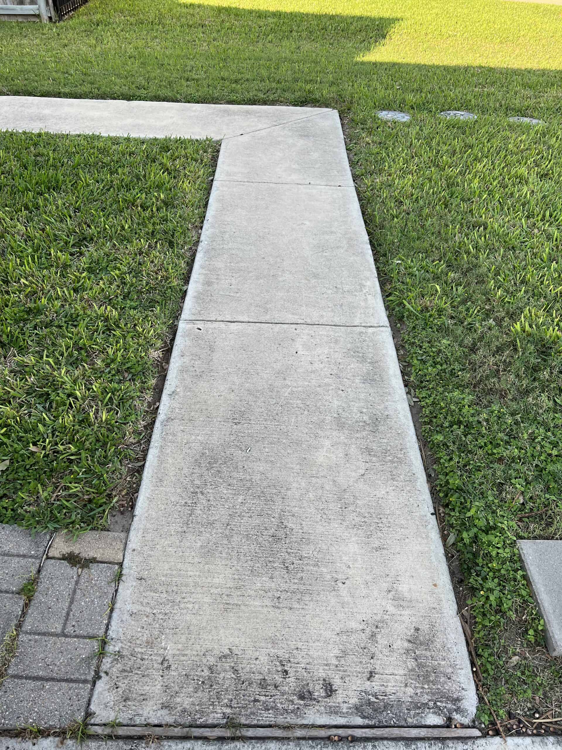 Concrete sidewalk half pressure washed showing the clean line