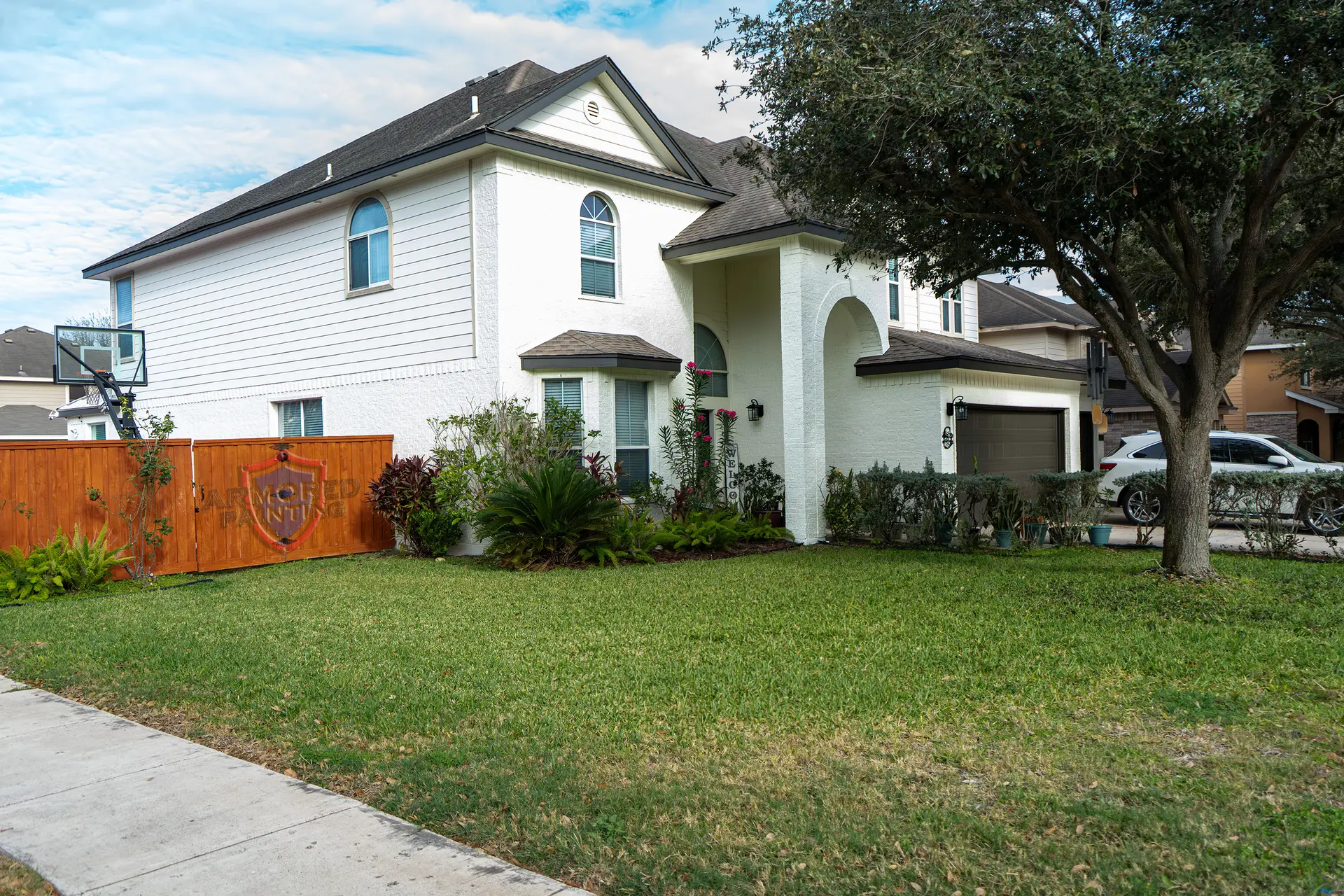 White two-story home with fresh trim and an Armored Painting yard sign